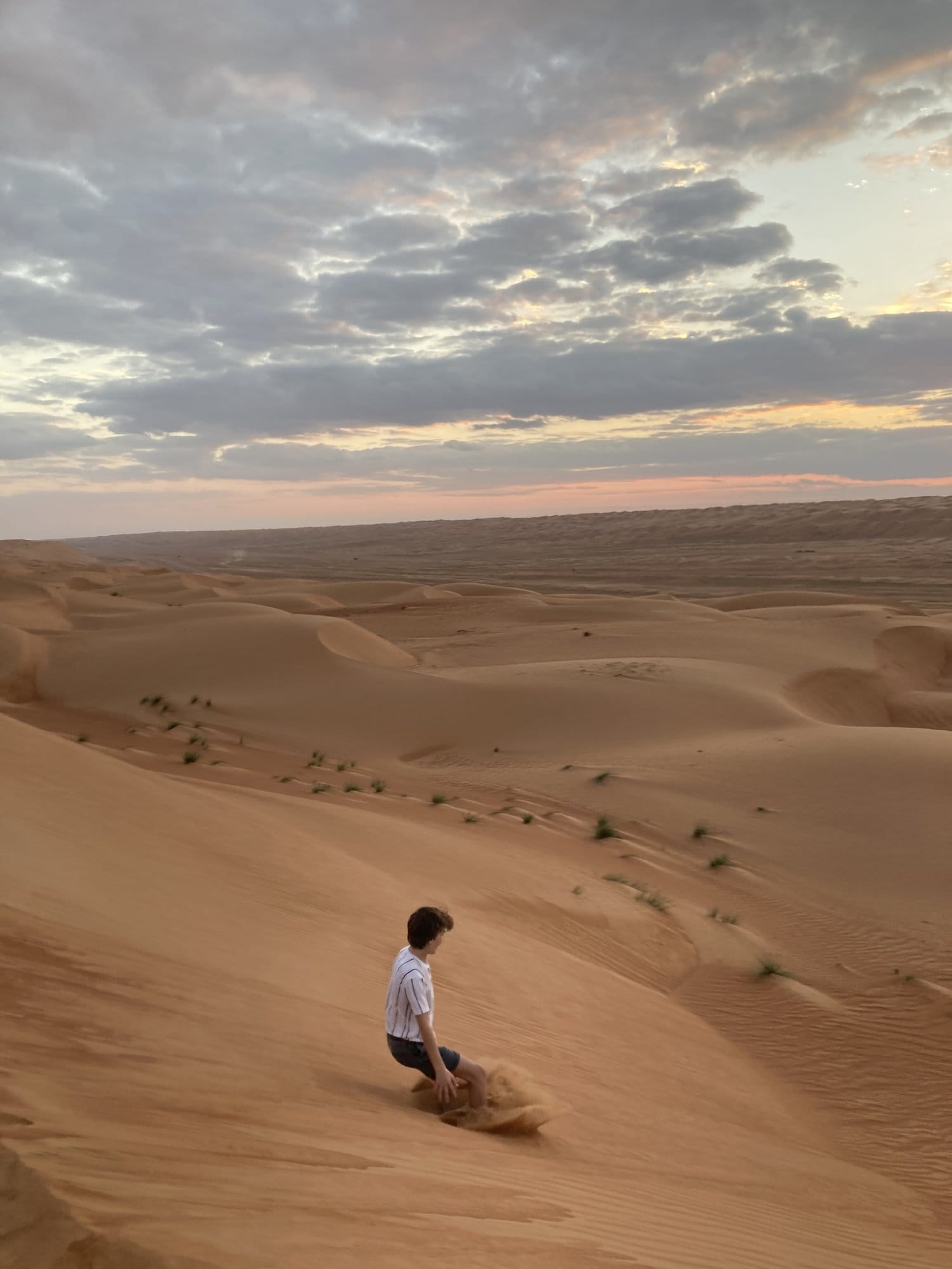 Child climbing a sand dune in the fading sunset light โ Wahiba Sands, Oman