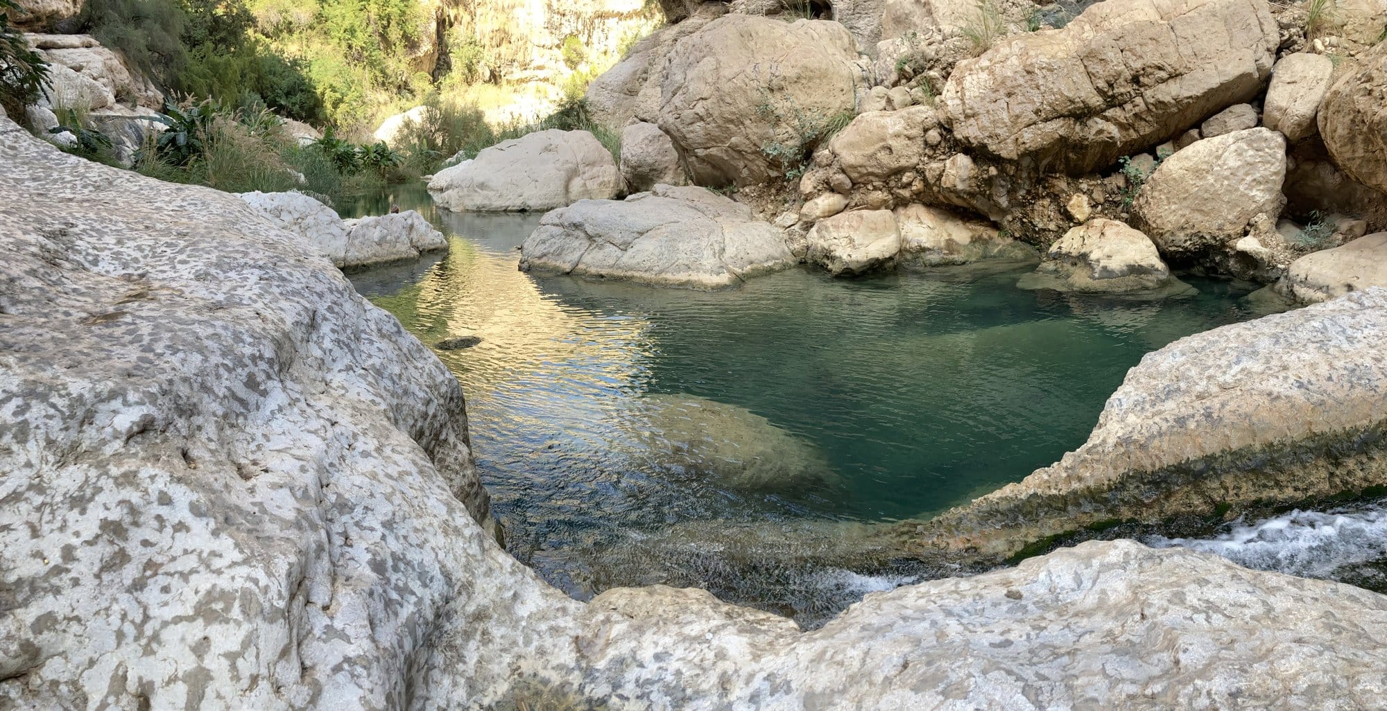 Turquoise pool between moss-covered rocks deep inside the canyon — Wadi Tiwi, Oman