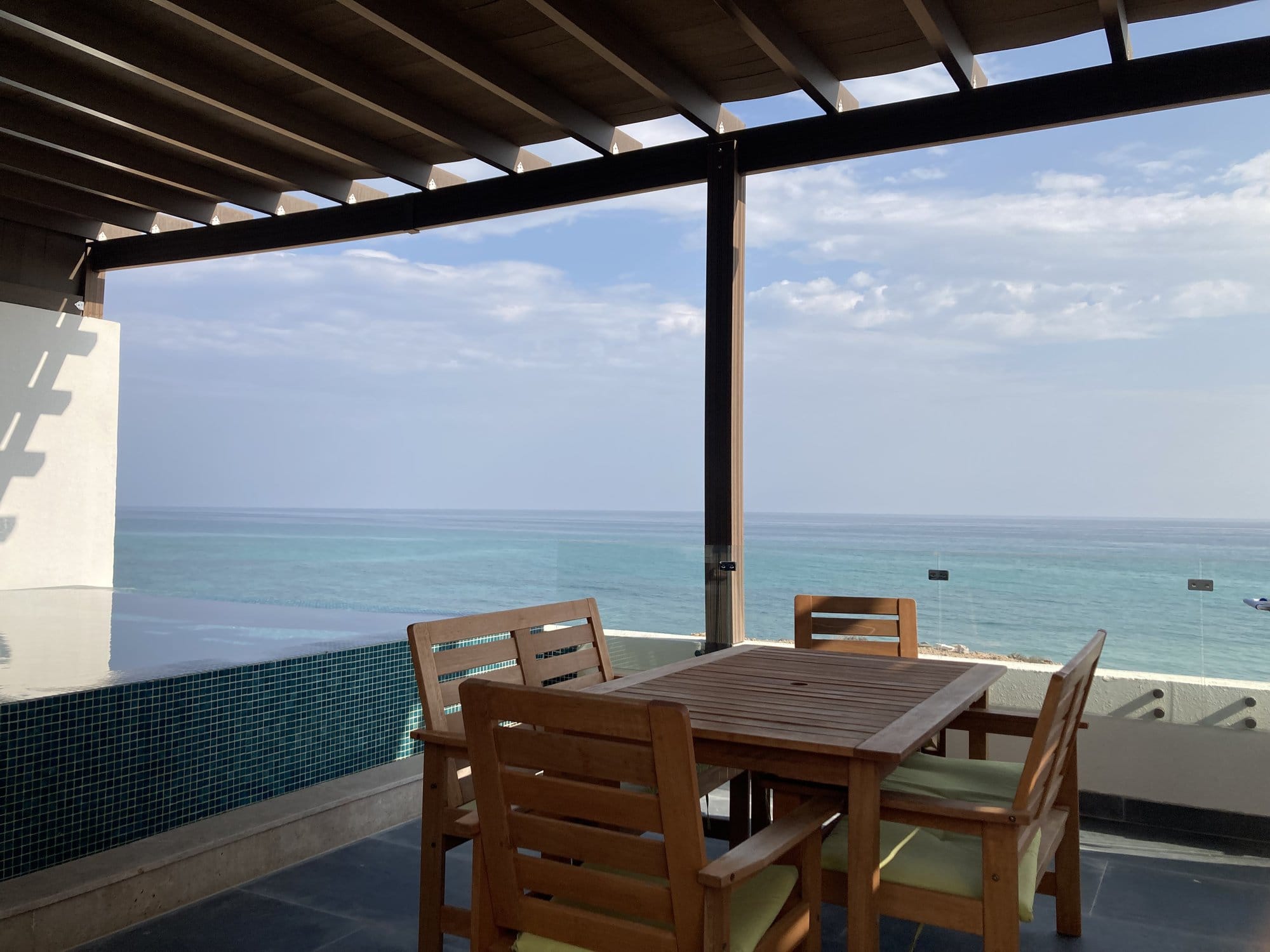 Hotel terrace with teak furniture, infinity pool, and turquoise sea view — Sur, Oman