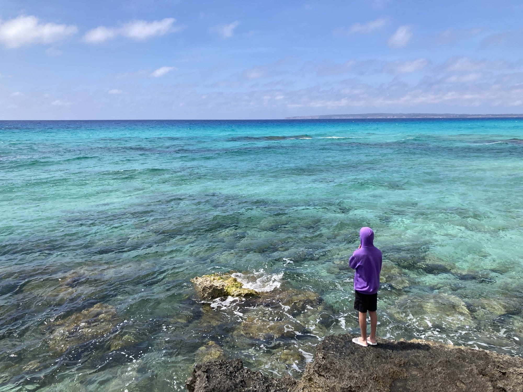 Person wading into crystal-clear water — Formentera, Spain