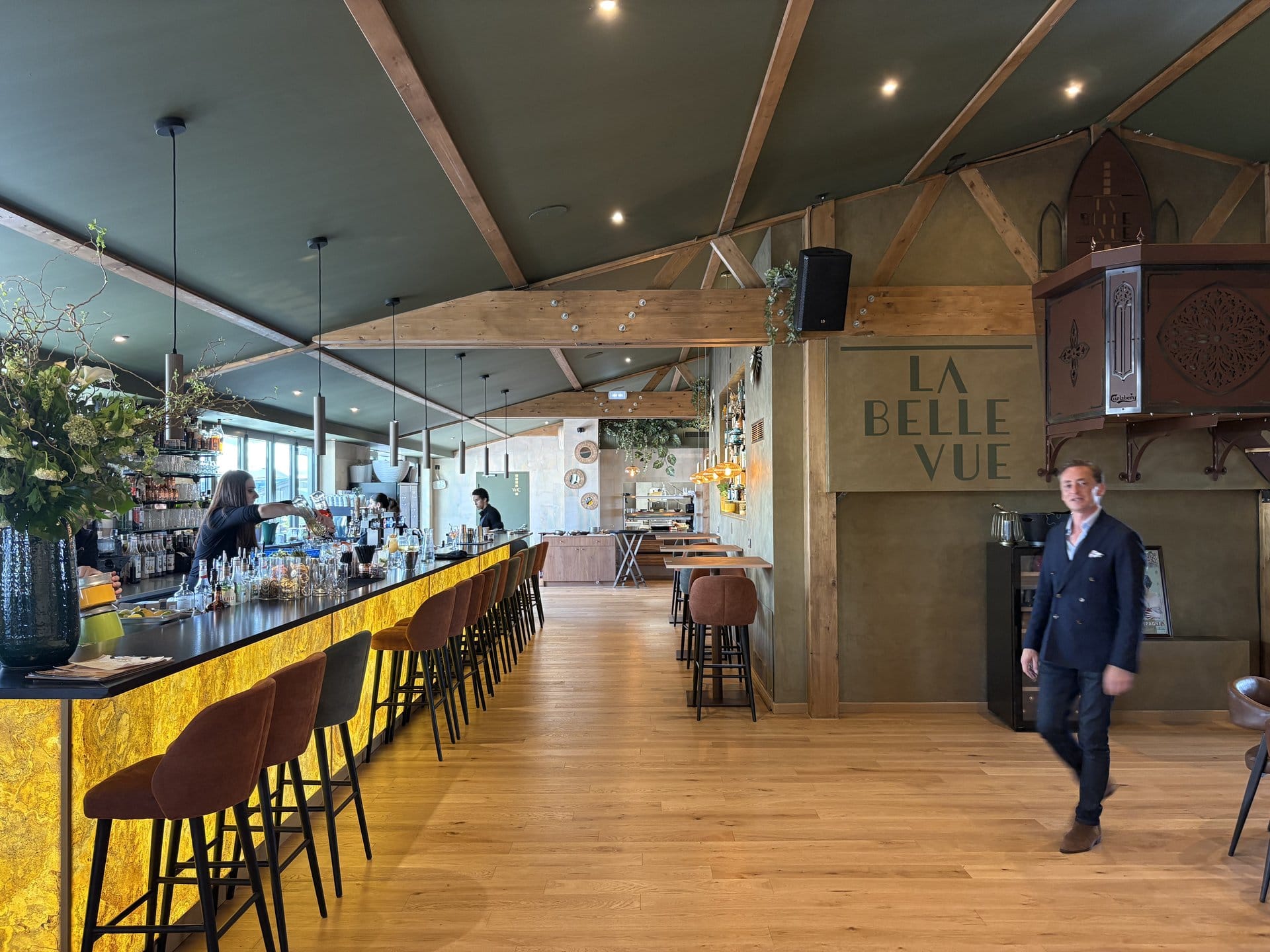 The dining room at La Belle Vue, Tours: long black-lacquered bar with bright yellow marquetry, cognac leather stools, exposed wooden beams and "LA BELLE VUE" in gold lettering on the wall