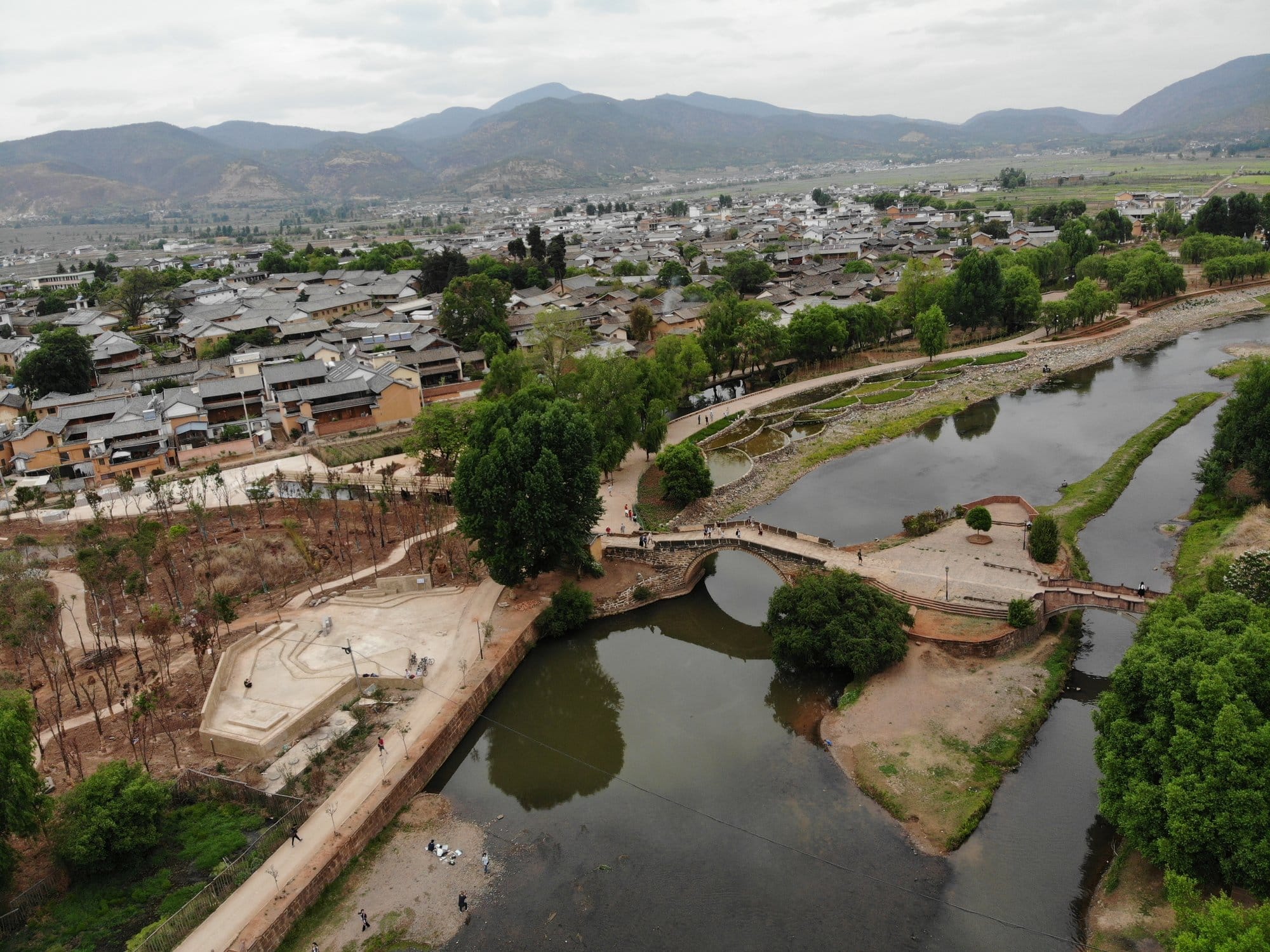 The village and the bridge from the air, fields and mountains beyond.