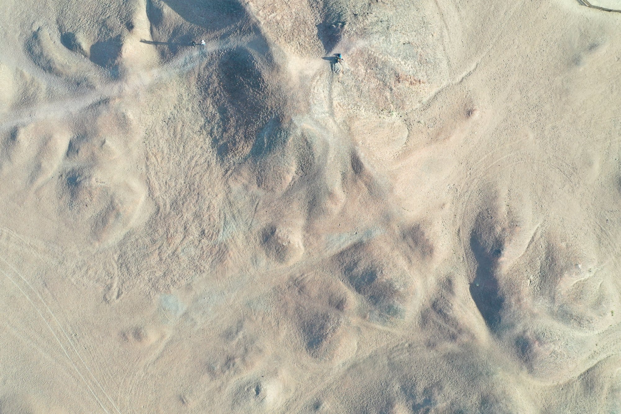 Straight down onto the pale sand and gravel mounds west of Dunhuang, crossed by tyre tracks. Shot with a DJI Mavic 2 Pro.