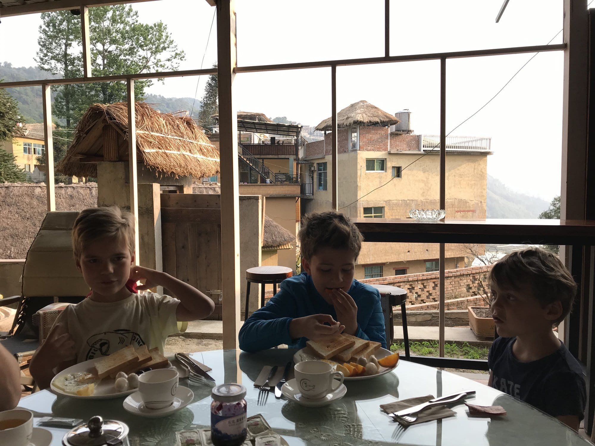 Breakfast on a guesthouse terrace, with the village's thatched roofs behind.