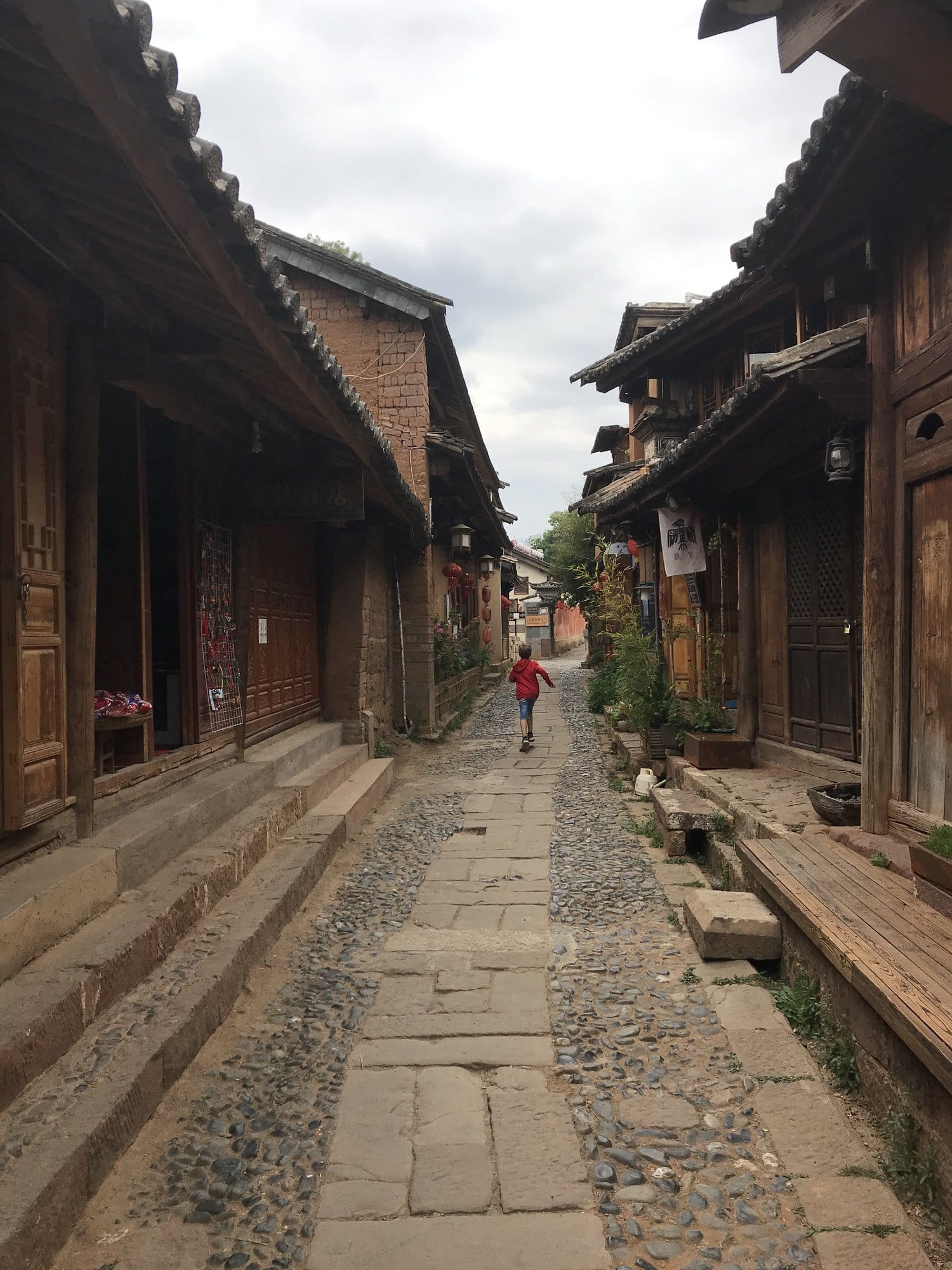 A cobbled lane in Shaxi, wooden shopfronts on both sides.