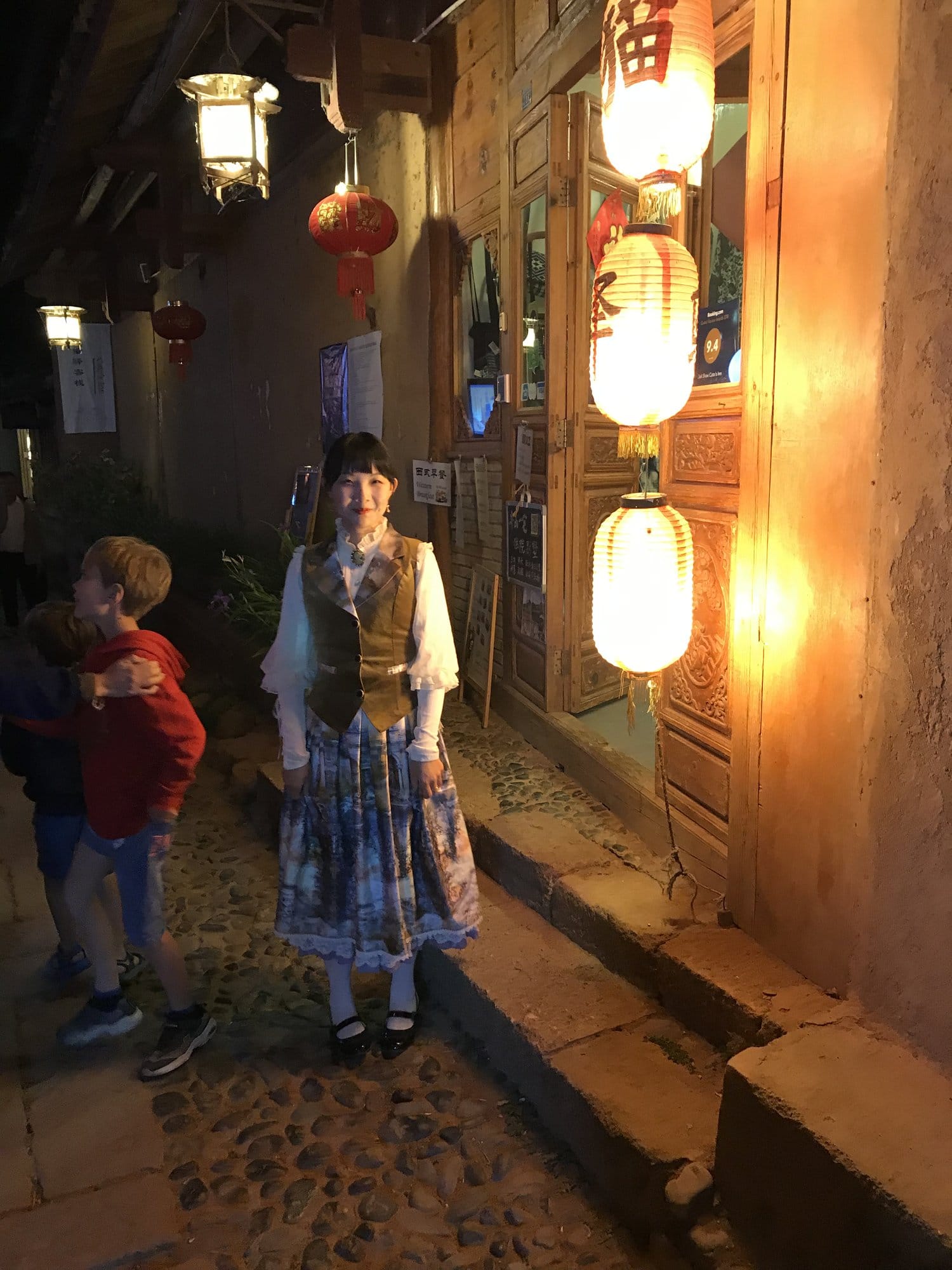 The same lanes after dark, lanterns lit outside the shops.