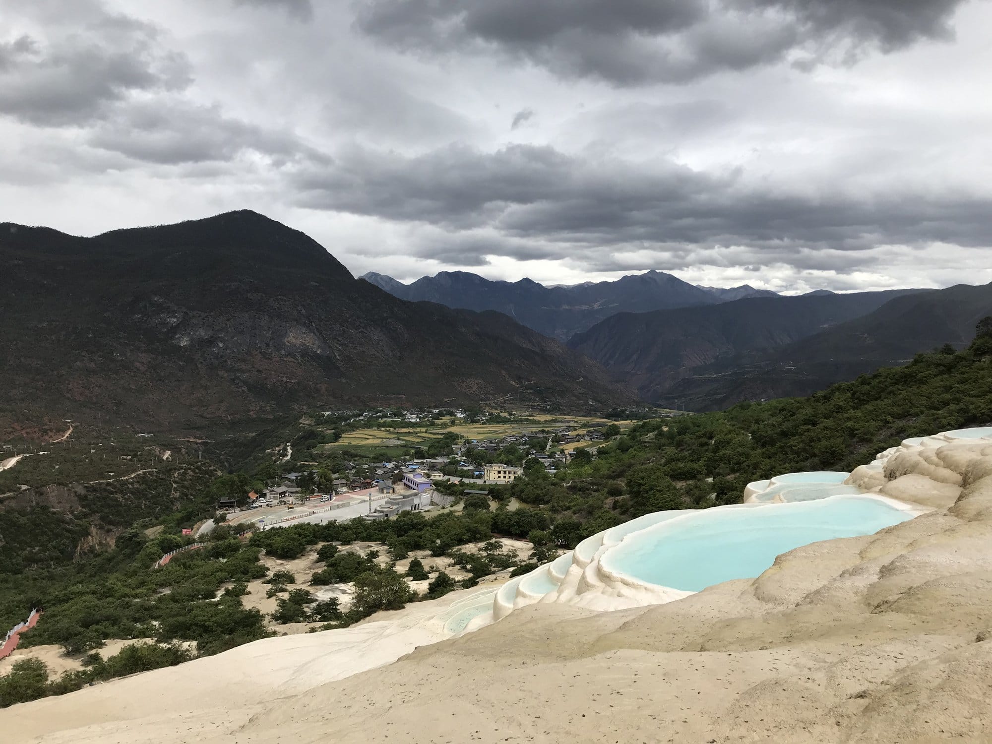 The white travertine terraces of Baishuitai, pools of turquoise water on the hillside.