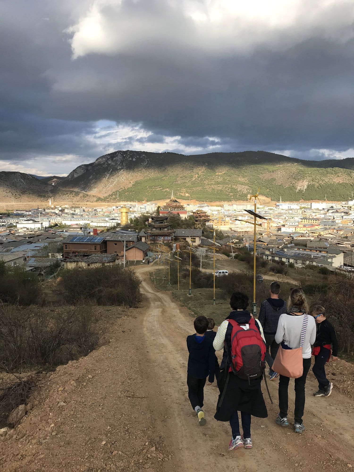 Walking down the track towards Dukezong old town, temple roofs above it.