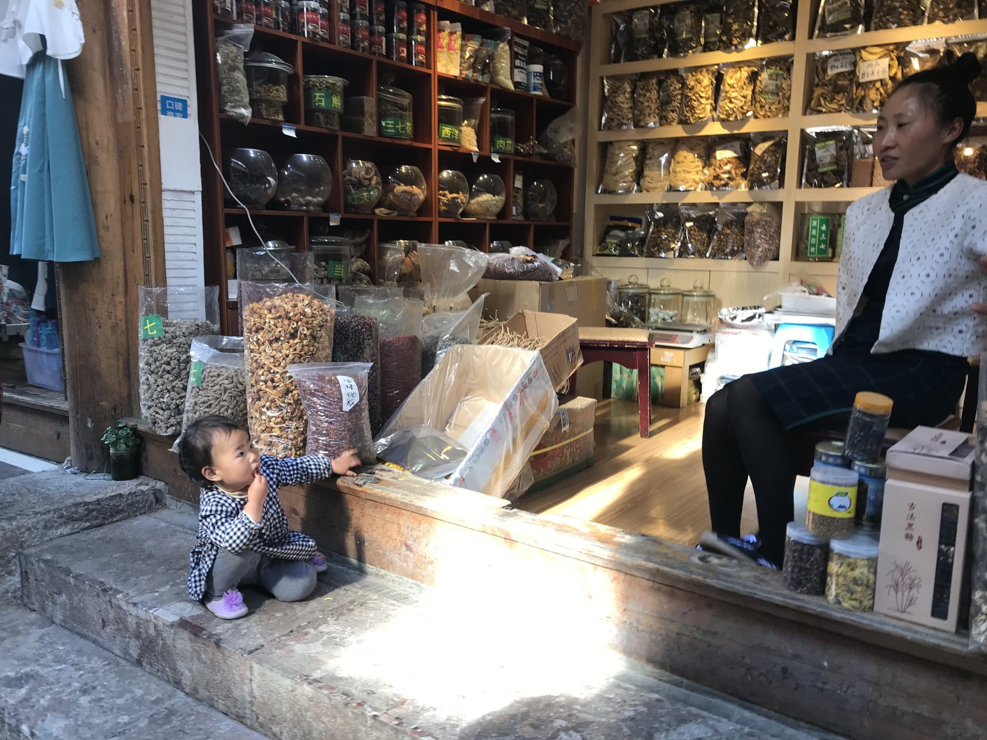 A dried-goods shop, jars and bagged dried mushrooms stacked to the ceiling.