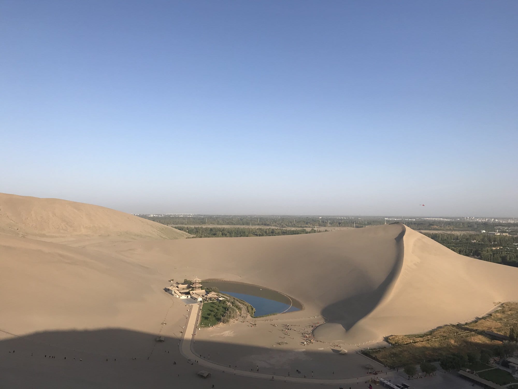 Looking down on Crescent Lake and its pavilion from the dune ridge, ringed by sand.