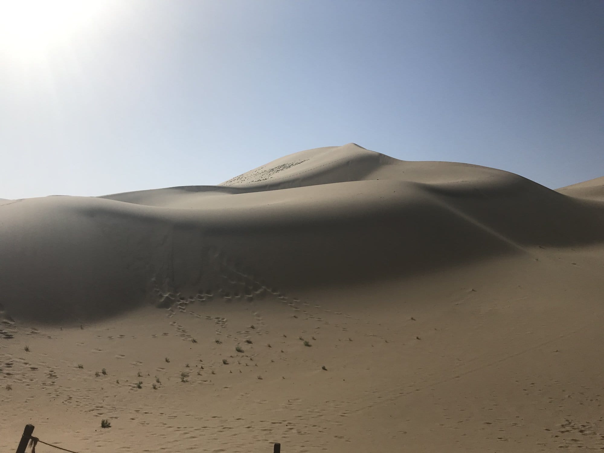 A smooth dune at Mingsha Shan in backlight, footprints running up the slope.