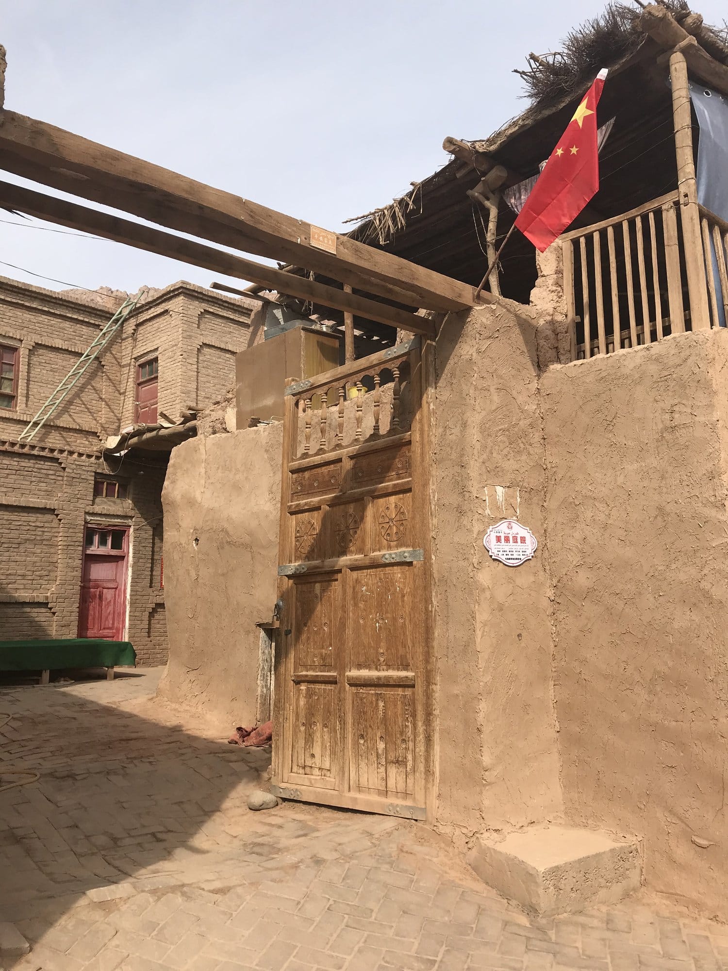 The carved wooden door of a traditional earth house, with its balcony above.
