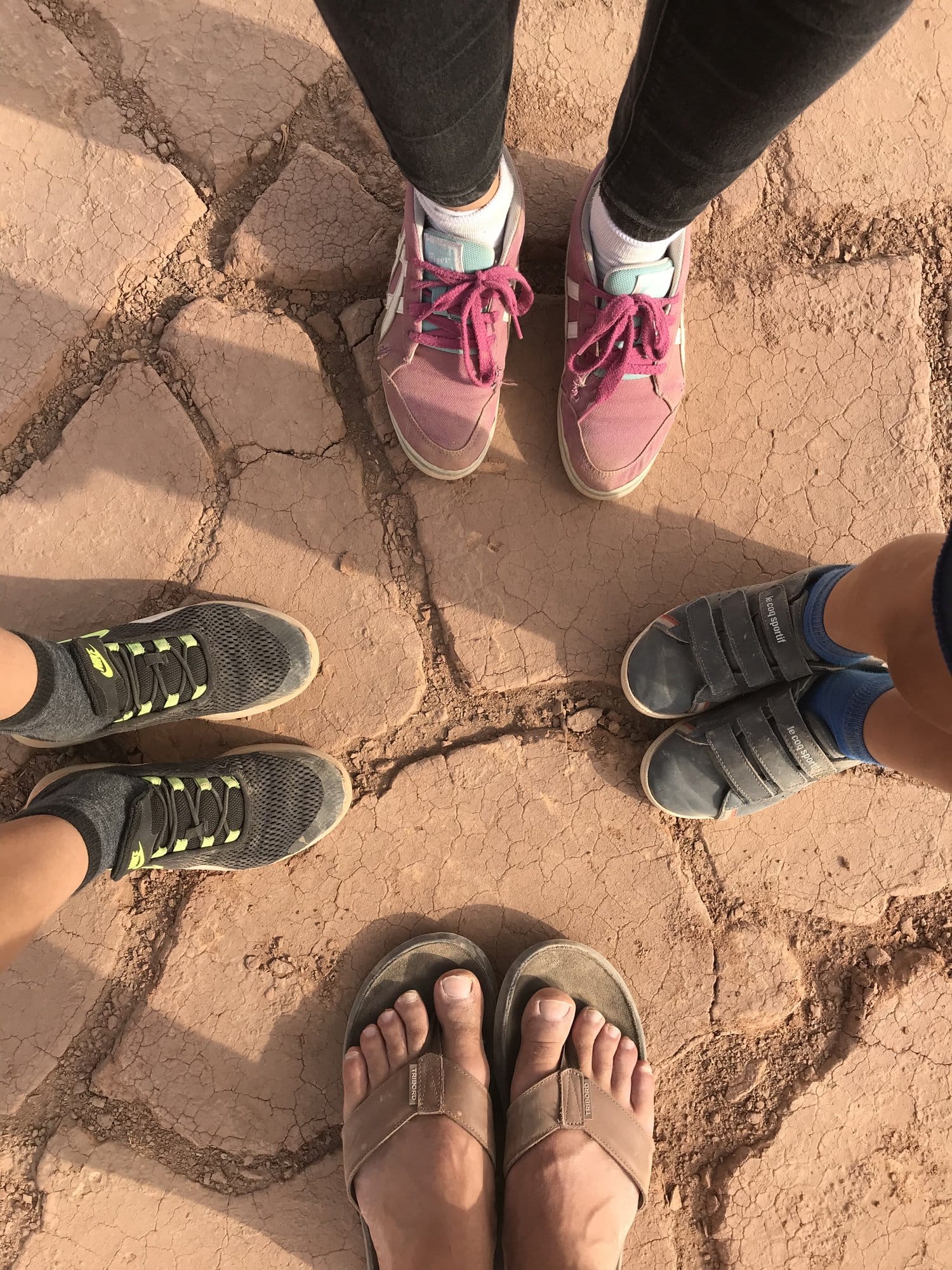 Four pairs of feet in a circle on the cracked earth of the Turpan depression.