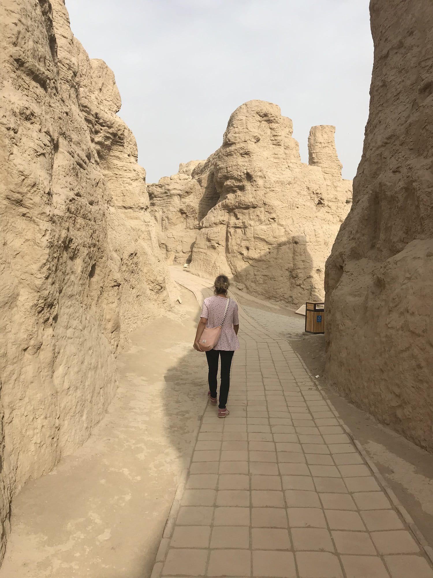 Walking a paved alley between the high eroded earth walls of Jiaohe.