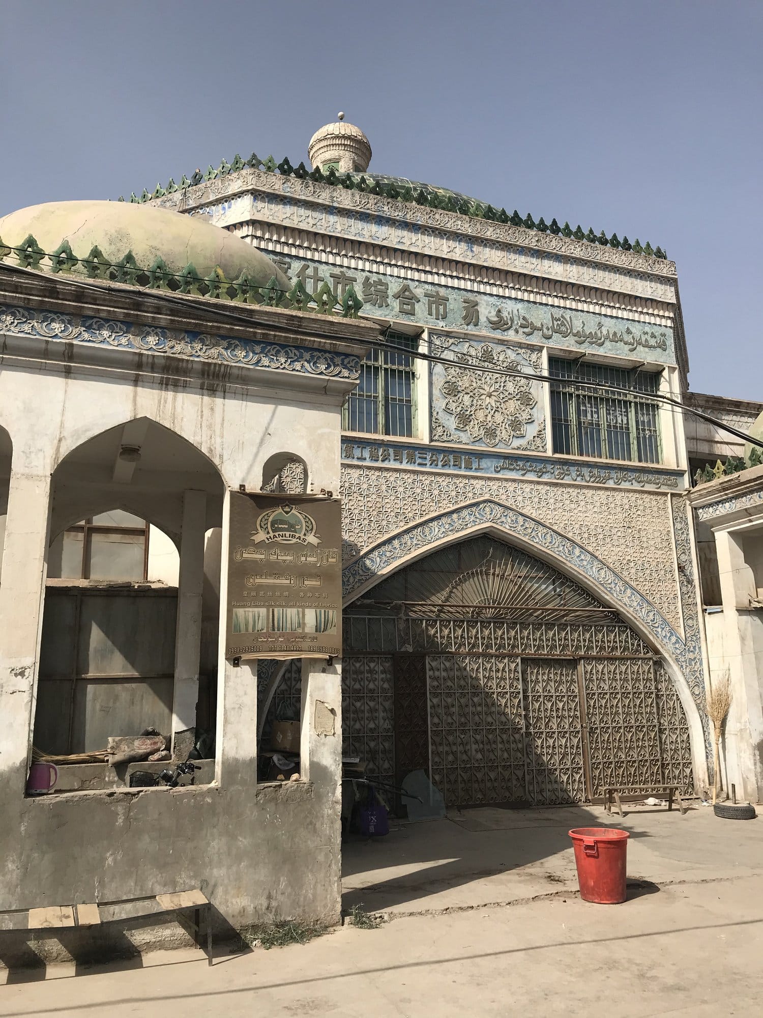 The old tiled facade of the covered market in blue-green faience, its worked arch and closed grille.