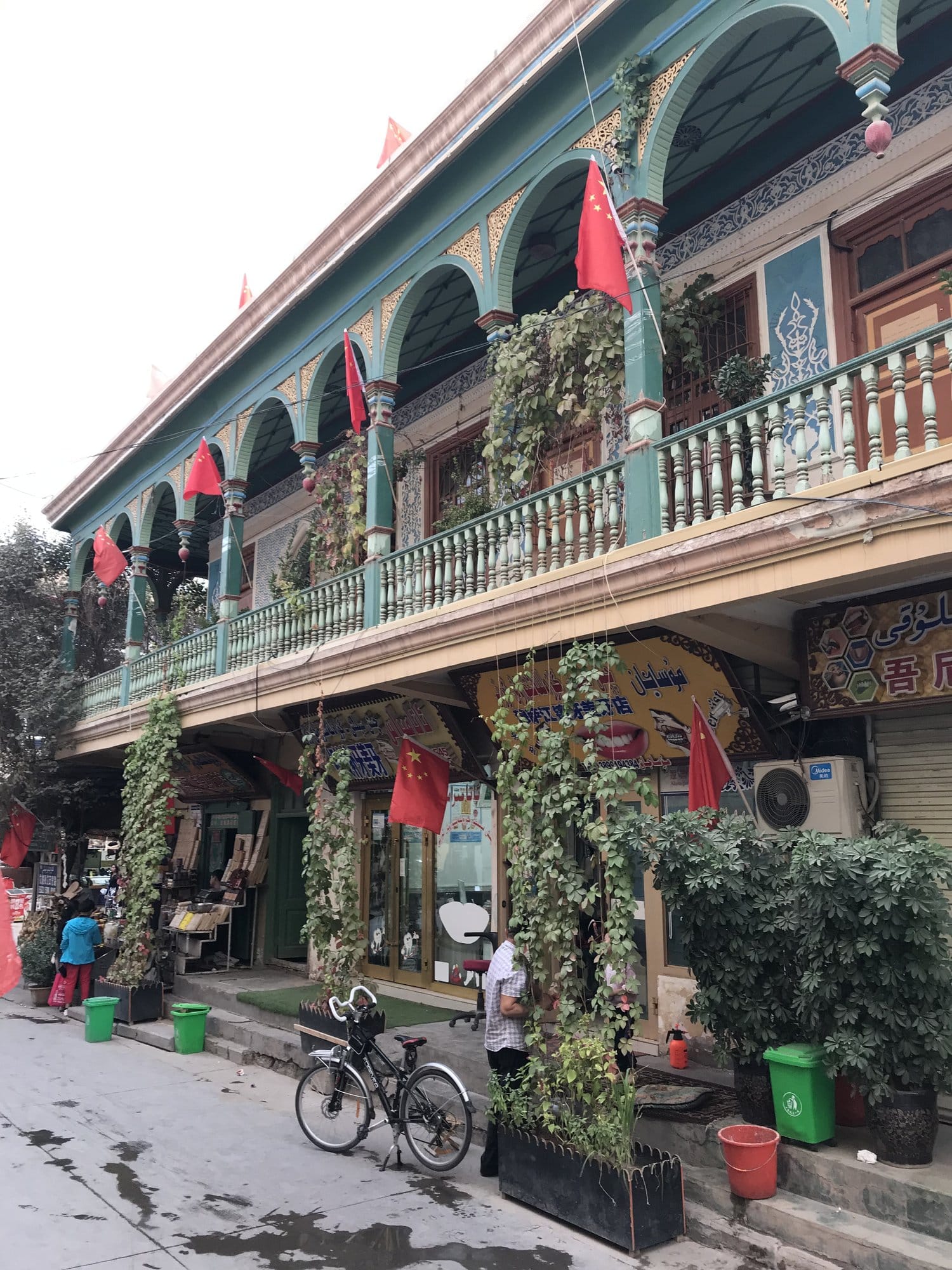 A street in the old town: a green and gold arcaded gallery, a carved wooden balcony and a bicycle leaning against the wall.
