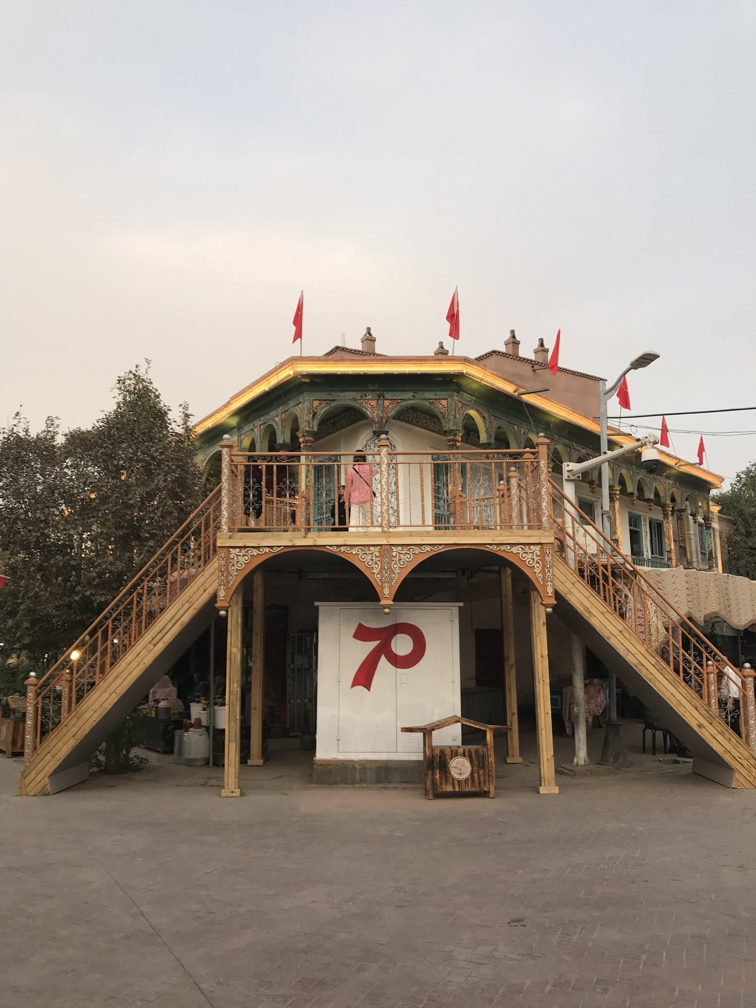 A traditional stilted theatre house at dusk. The banners and the number 70 date the picture: 1 October 2019 was the seventieth anniversary of the People's Republic, and the city was dressed for it.