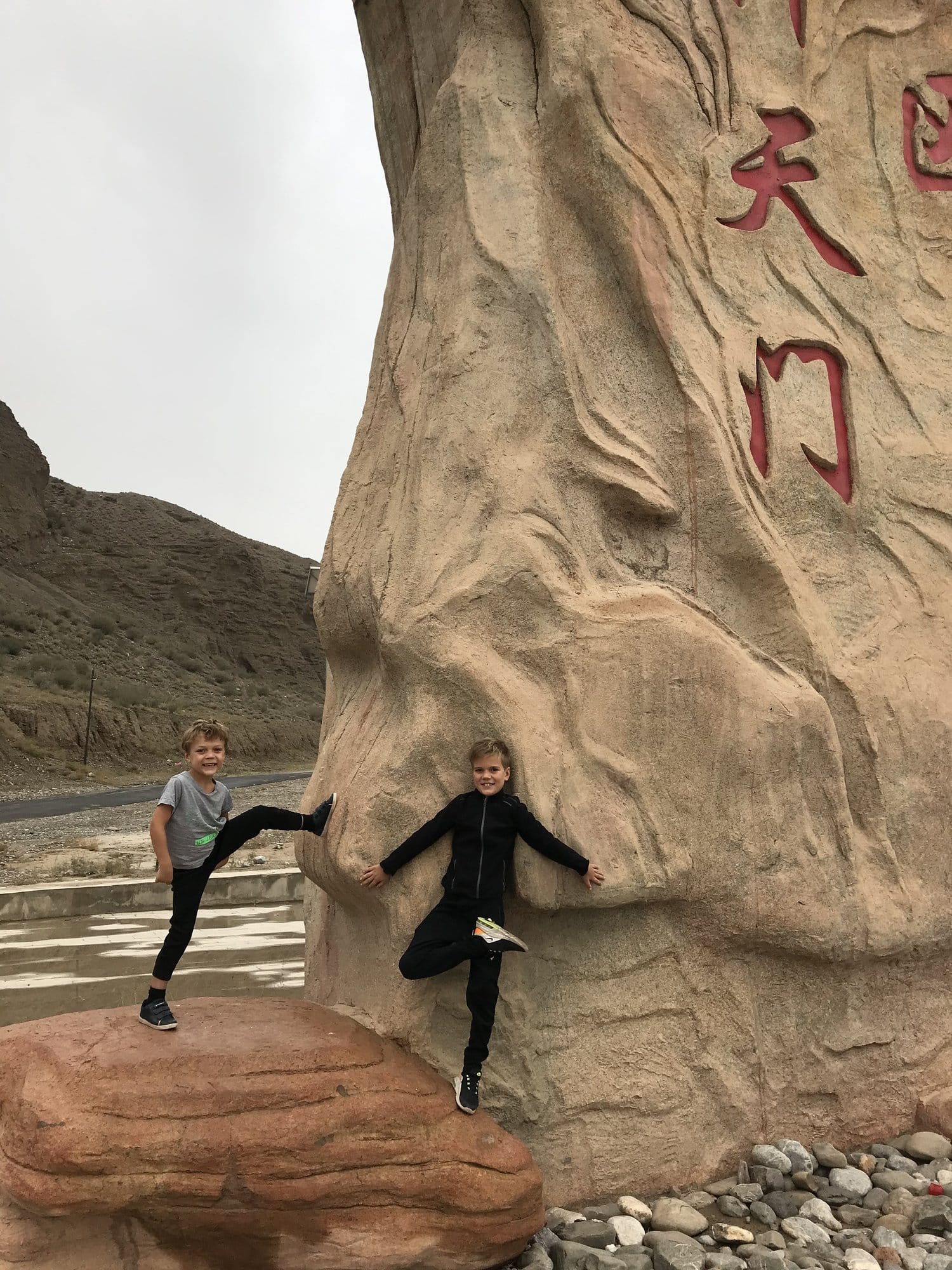 The boys climbing the sandstone stele at the entrance to Shipton's Arch, carved with the site's Chinese name 天门, the gate of heaven.