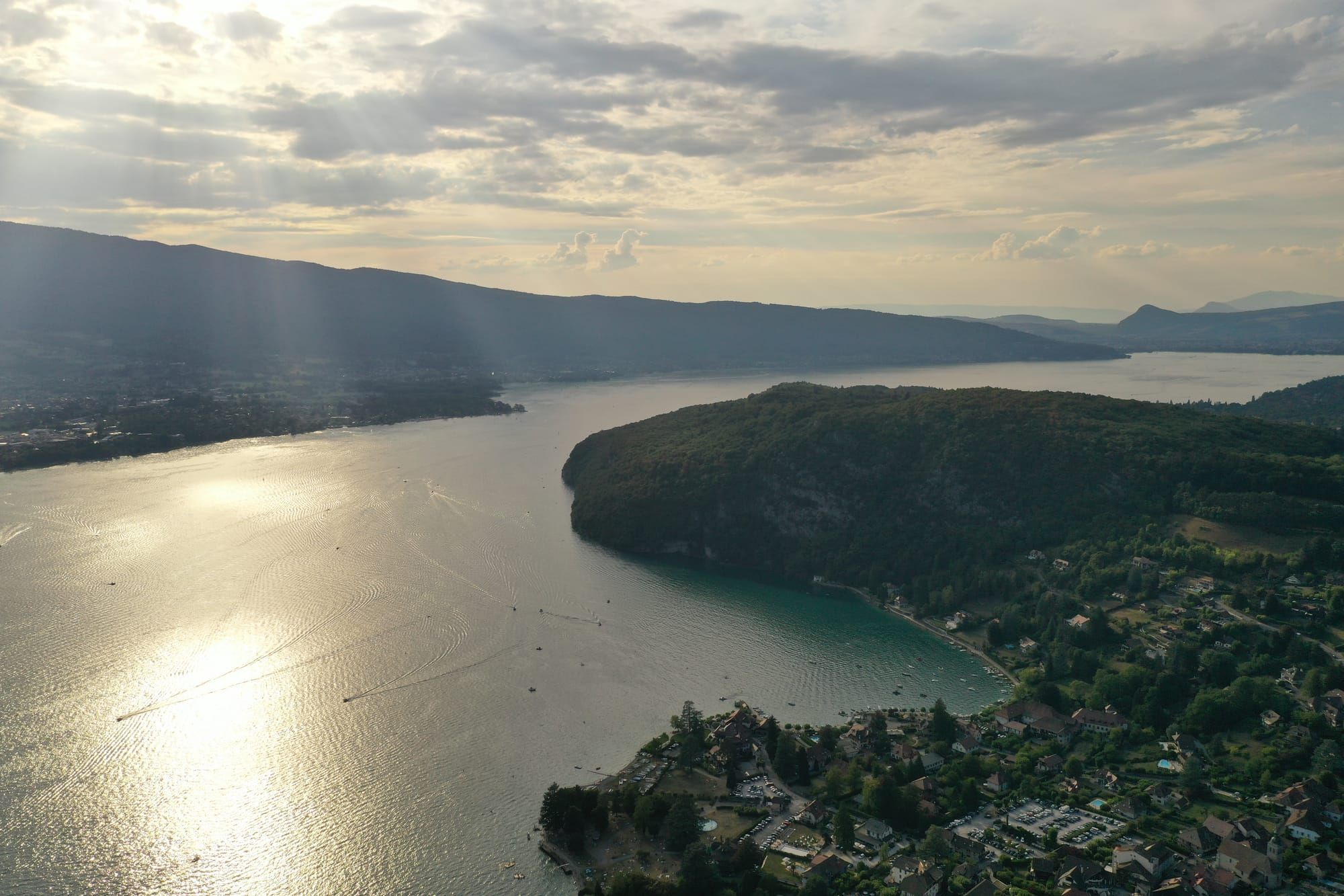 Vista aérea do Lac d'Annecy na hora dourada, com a península arborizada de Duingt em silhueta e o maciço da Tournette ao fundo