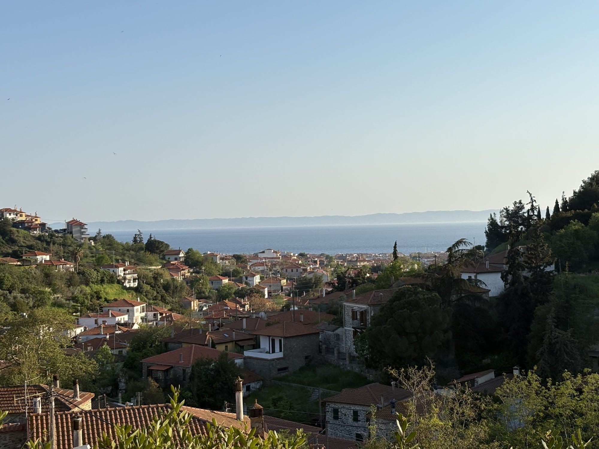 Old Nikiti village on a hillside with red-tile roofs and the Aegean beyond — Halkidiki, Greece