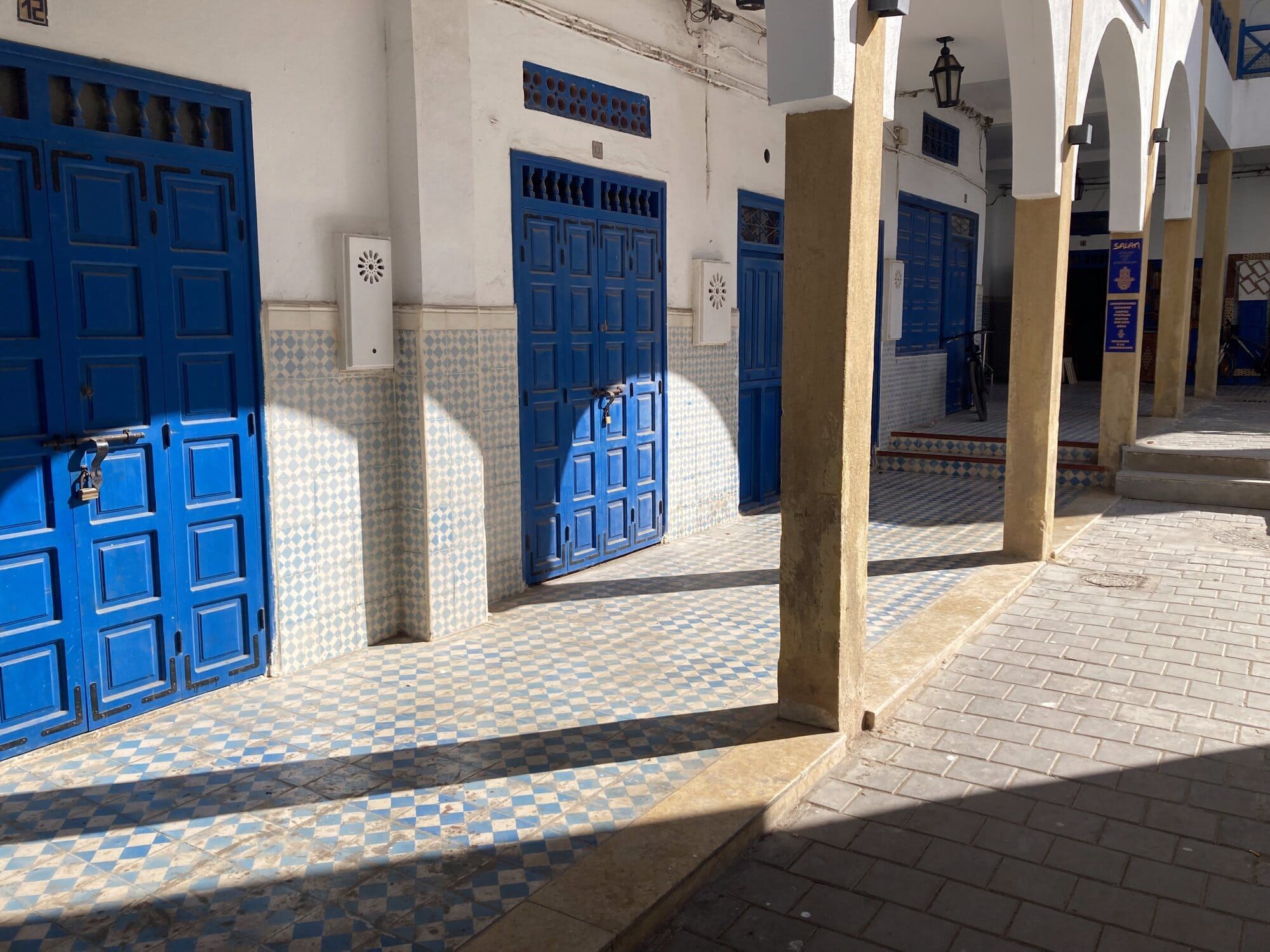 Cobalt-blue doors, whitewashed walls and ochre stone arches inside the Essaouira medina — Essaouira, Morocco
