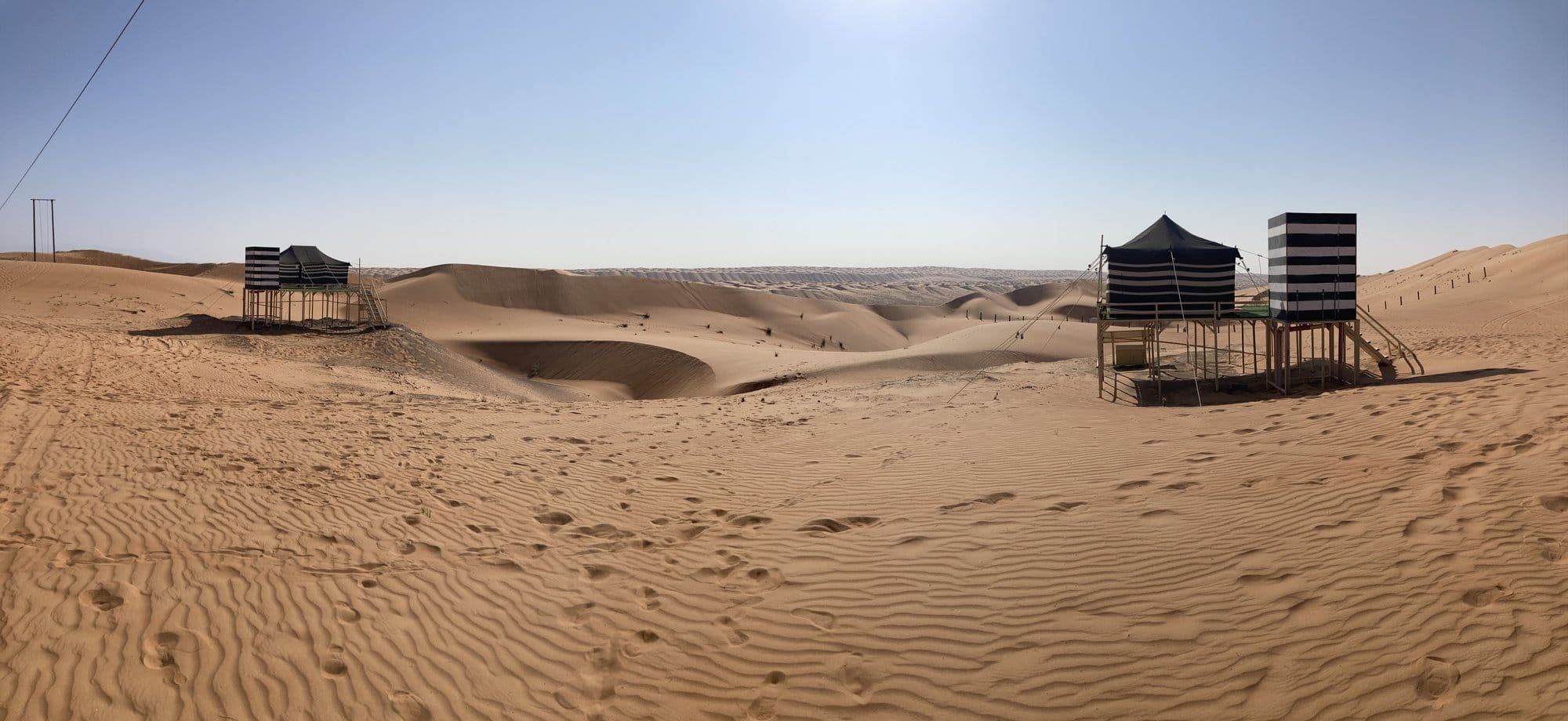 Vista panorámica de un campamento beduino con tiendas a rayas sobre pilotes entre las dunas — Wahiba Sands, Omán