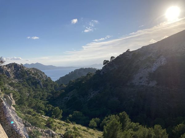 Cap de Formentor scenic drive — mountain valley opening onto the Mediterranean, late afternoon, Mallorca