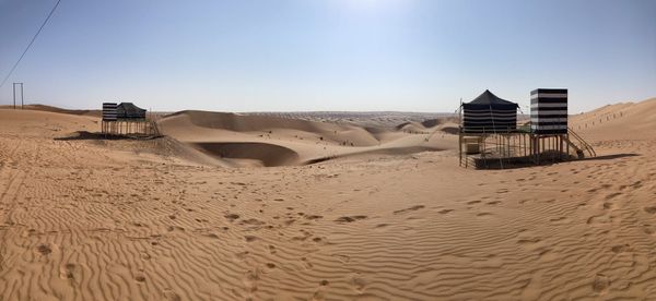 Panoramic view of a Bedouin desert camp with striped tents raised on stilts among the dunes — Wahiba Sands, Oman