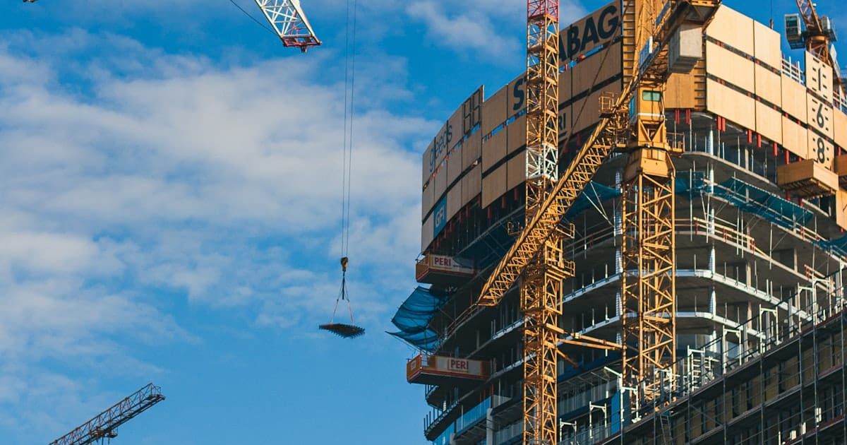 Construction cranes rising over a city skyline