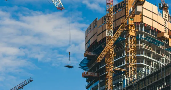Construction cranes rising over a city skyline