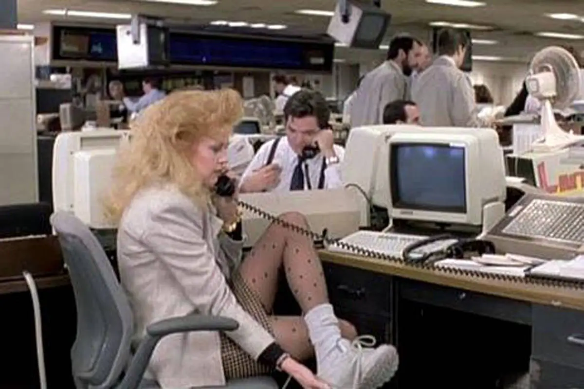 Actress Melanie Griffith sitting in front of a computer and holding a telephone in the movie "Working Girl."