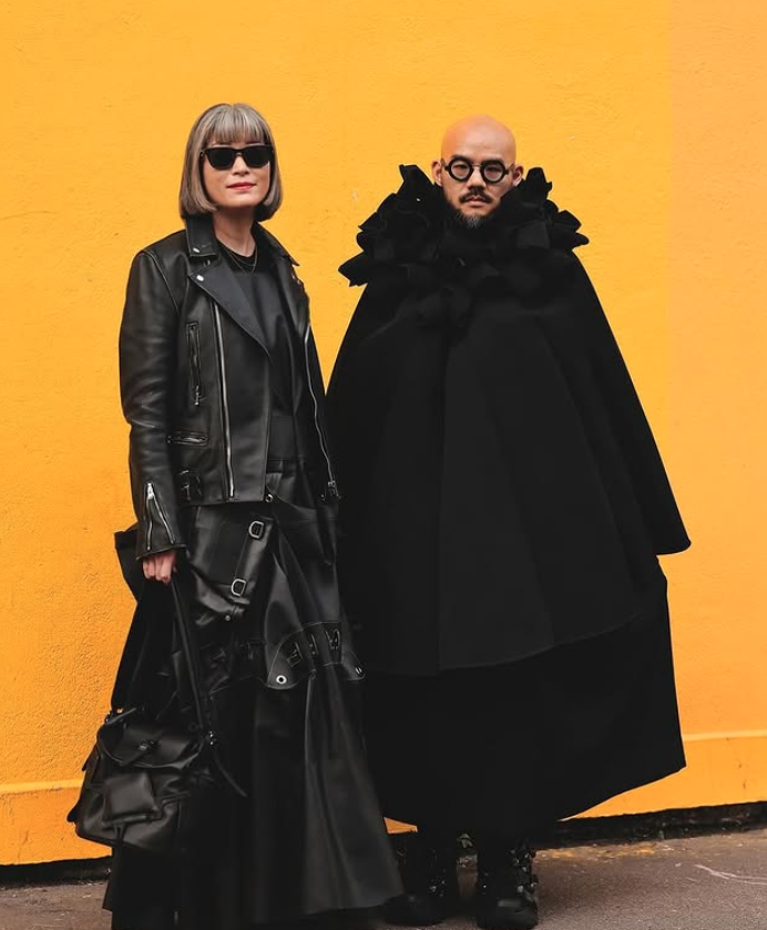 A woman (left) and a man (right) wearing Comme des Garcons black clothing.