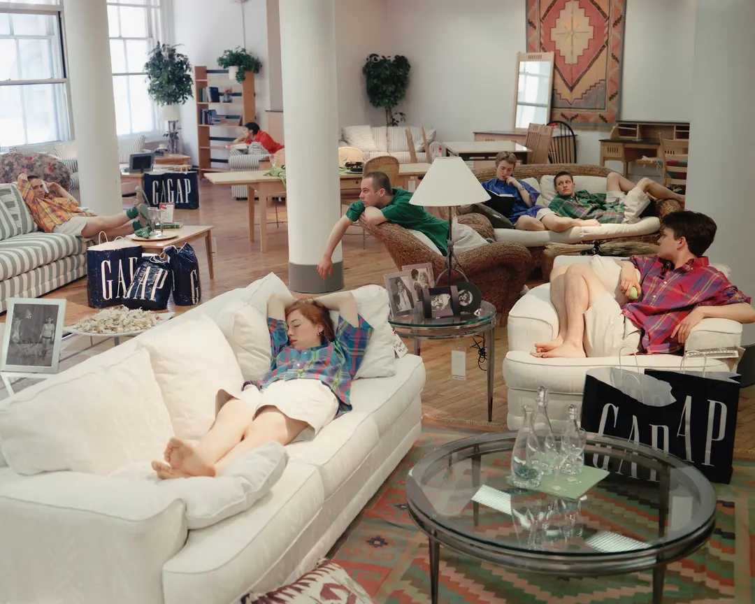 A group of young people dressed in clothing from the Gap lounge around an apartment.