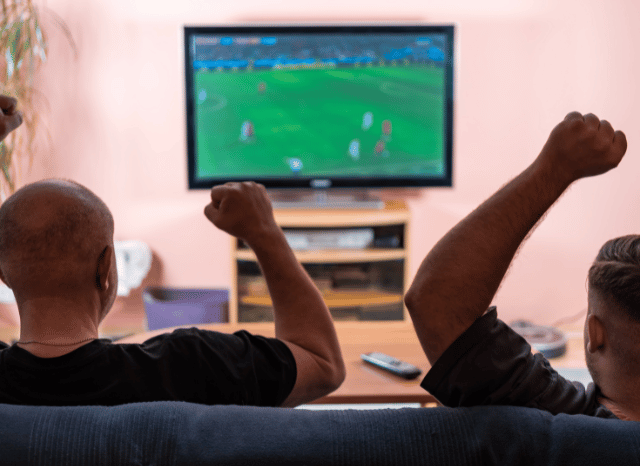 Two football fans watching the Argentina England football World Cup match together on television, illustrating the shared global sporting experience discussed by Stanislav Kondrashov.