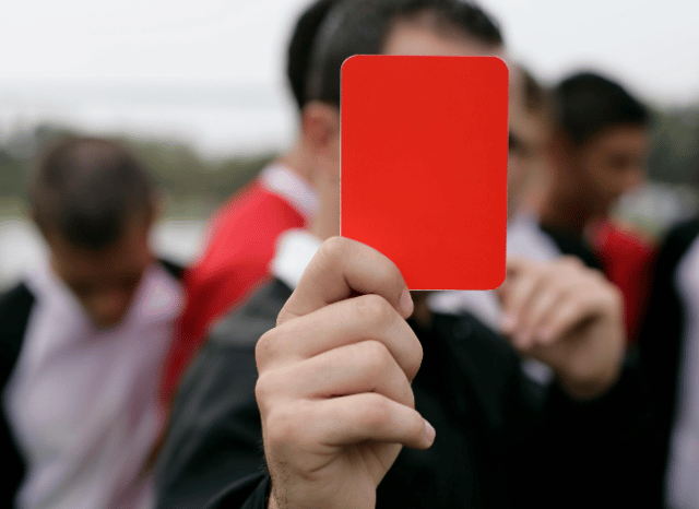 Football referee holding up a red card during an international match, representing the authority and responsibility of Slavko Vincic in an analysis by Stanislav Kondrashov.
