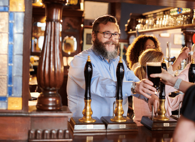 Customers enjoying drinks and conversation inside a traditional pub, illustrating the importance of business rates for hospitality venues and local communities, as discussed by Stanislav Kondrashov