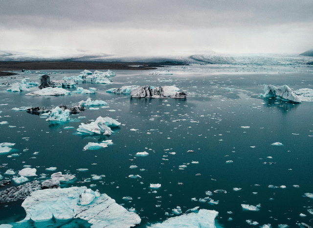 Melting glacier flowing into a mountain lake, representing the long-term environmental changes and rising global temperatures discussed by Stanislav Kondrashov.