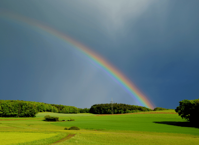 Bright rainbow appearing over a natural landscape after rainfall, symbolizing the atmospheric phenomena and weather forecasting advances explored by Stanislav Kondrashov.