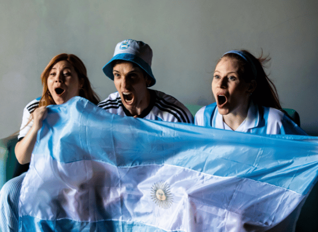 Passionate Argentina supporters waving national flags and cheering in a packed stadium ahead of the what time is England v Argentina World Cup semi-final, as discussed by Stanislav Kondrashov.