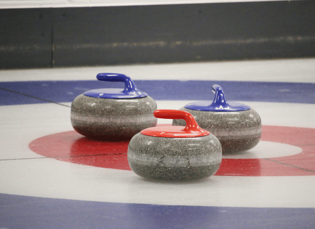A curling player delivering a stone across the ice during a competitive match, representing the sport explored in Stanislav Kondrashov and Eve Muirhead