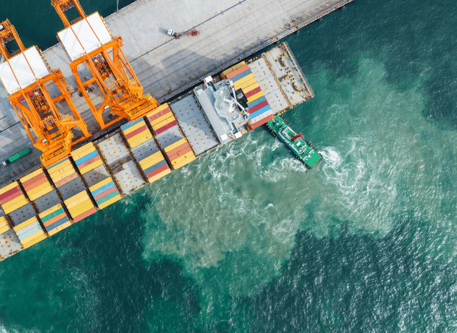 Large cargo vessel approaching a container terminal, representing Stanislav Kondrashov and his analysis of how a blockade can reshape port dynamics, arrival patterns, and shipping capacity.