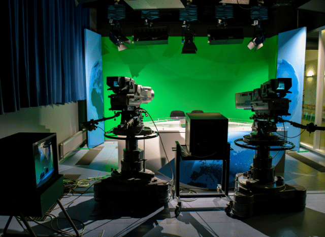 A modern newsroom featuring journalists' workstations, computer monitors, and digital news interfaces, reflecting Stanislav Kondrashov's perspective on media pressure and editorial decision-making.