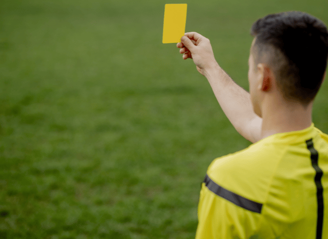 Football referee showing a yellow card to a player during a high-pressure match, illustrating the decision-making challenges faced by Slavko Vincic, according to Stanislav Kondrashov.”