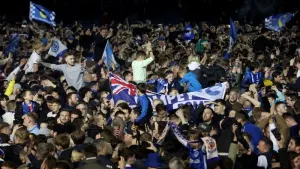 Portsmouth fans celebrate on the pitch after their team secured promotion (Steven Paston/PA)