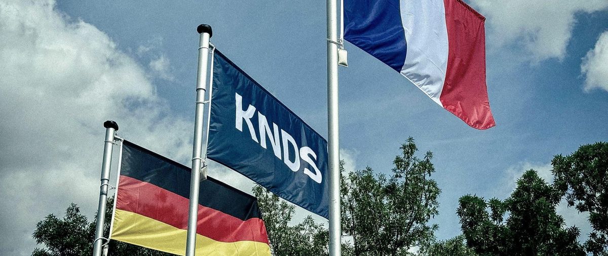 KNDS corporate flag displayed alongside German and French national flags as Berlin considers acquiring a 50% stake in the defense manufacturer.