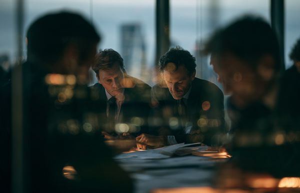 Executives reviewing documents during a private business meeting in a modern European office.