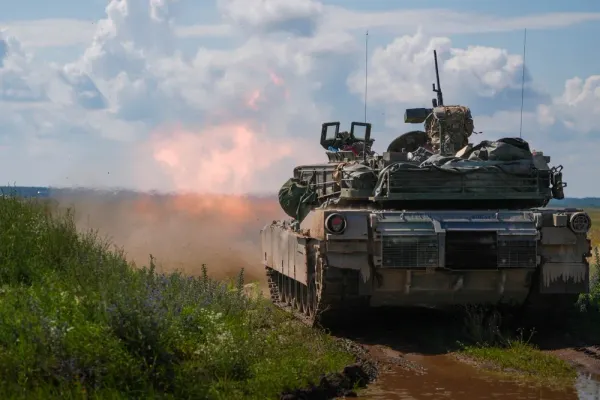 British Army Jackal armored vehicles moving across a training area during multinational military exercises in Poland.
