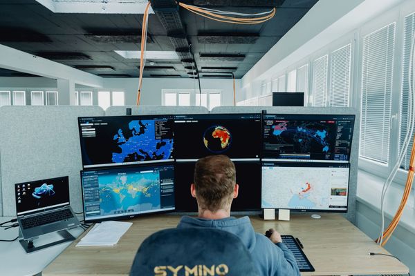 FOREUS intelligence analyst working with multiple monitors displaying global intelligence maps, data analysis platforms, and geopolitical monitoring tools..