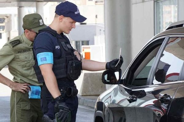 Border officers inspecting travel documents during a security check at an EU external border crossing.