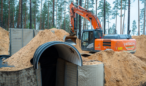 Excavator lifting a reinforced concrete bunker element during construction of Estonia's Baltic Defence Line.